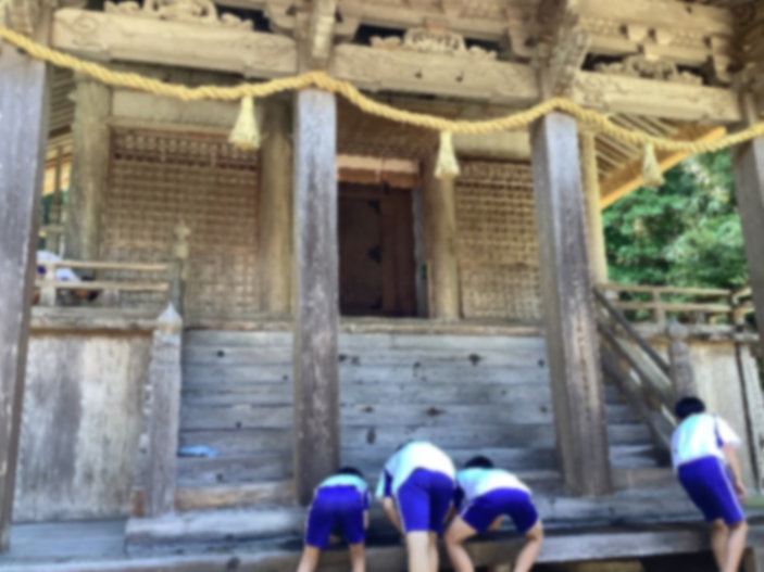 神社の拝殿前で児童たちが階段を掃除している写真