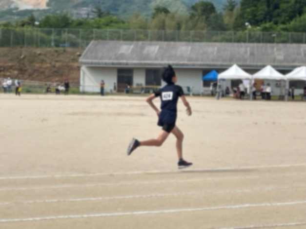 トラックを力強く走る一人の児童の後ろ姿の写真