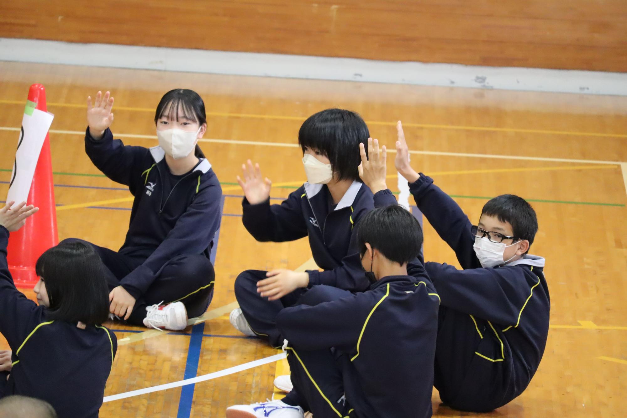 体育館で生徒たちが座って話し合い活動をする写真