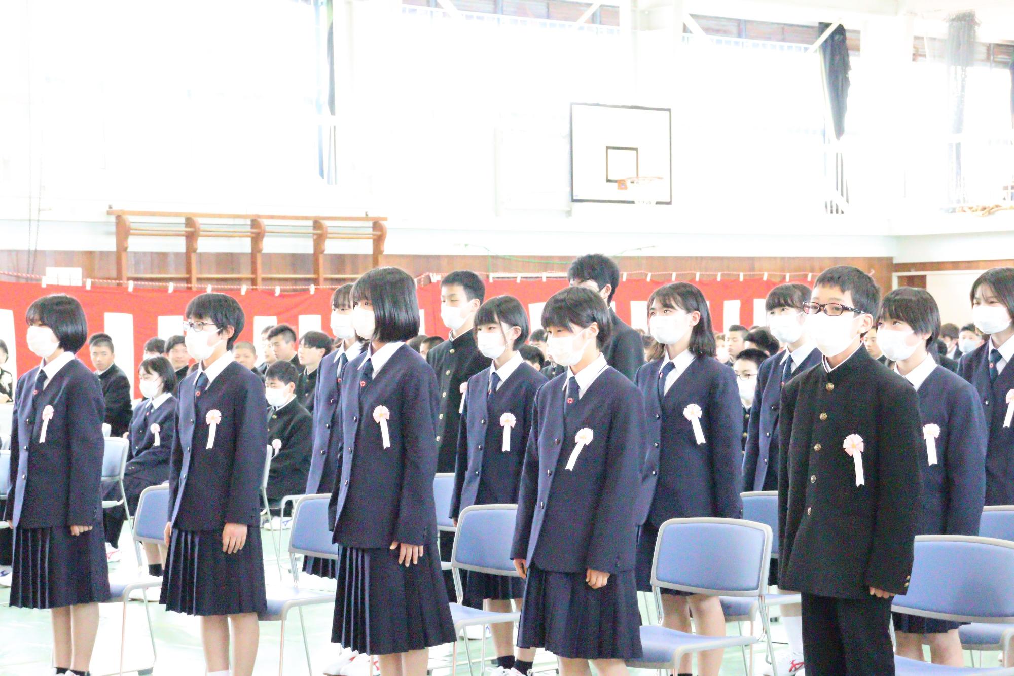 体育館で生徒が整列し入学式に臨む写真