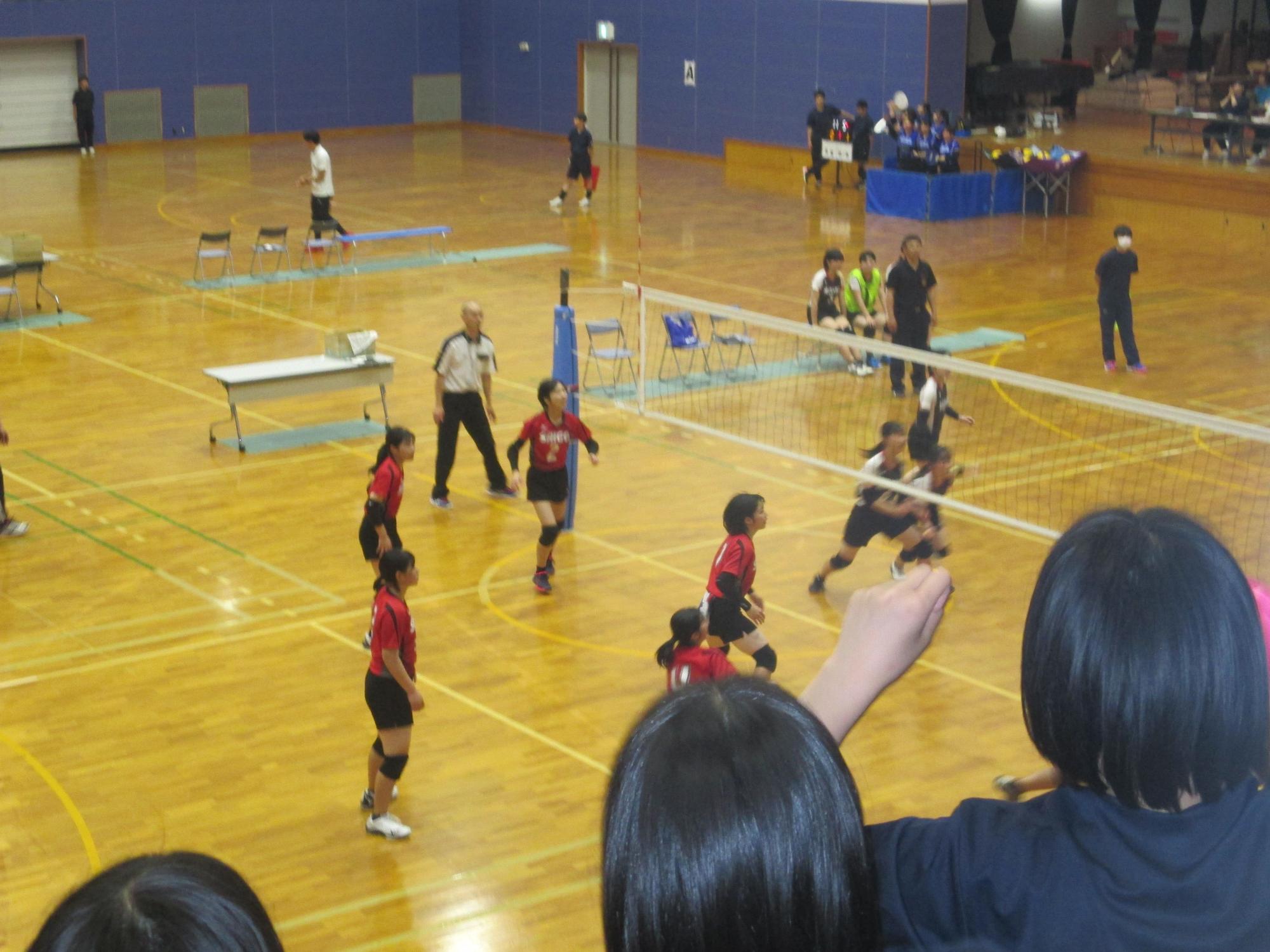 体育館で女子バレーボール部が試合をする写真