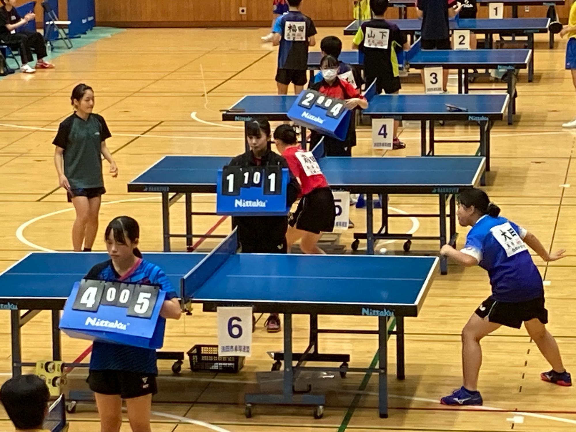 体育館で卓球部の大会試合をする生徒たちの写真