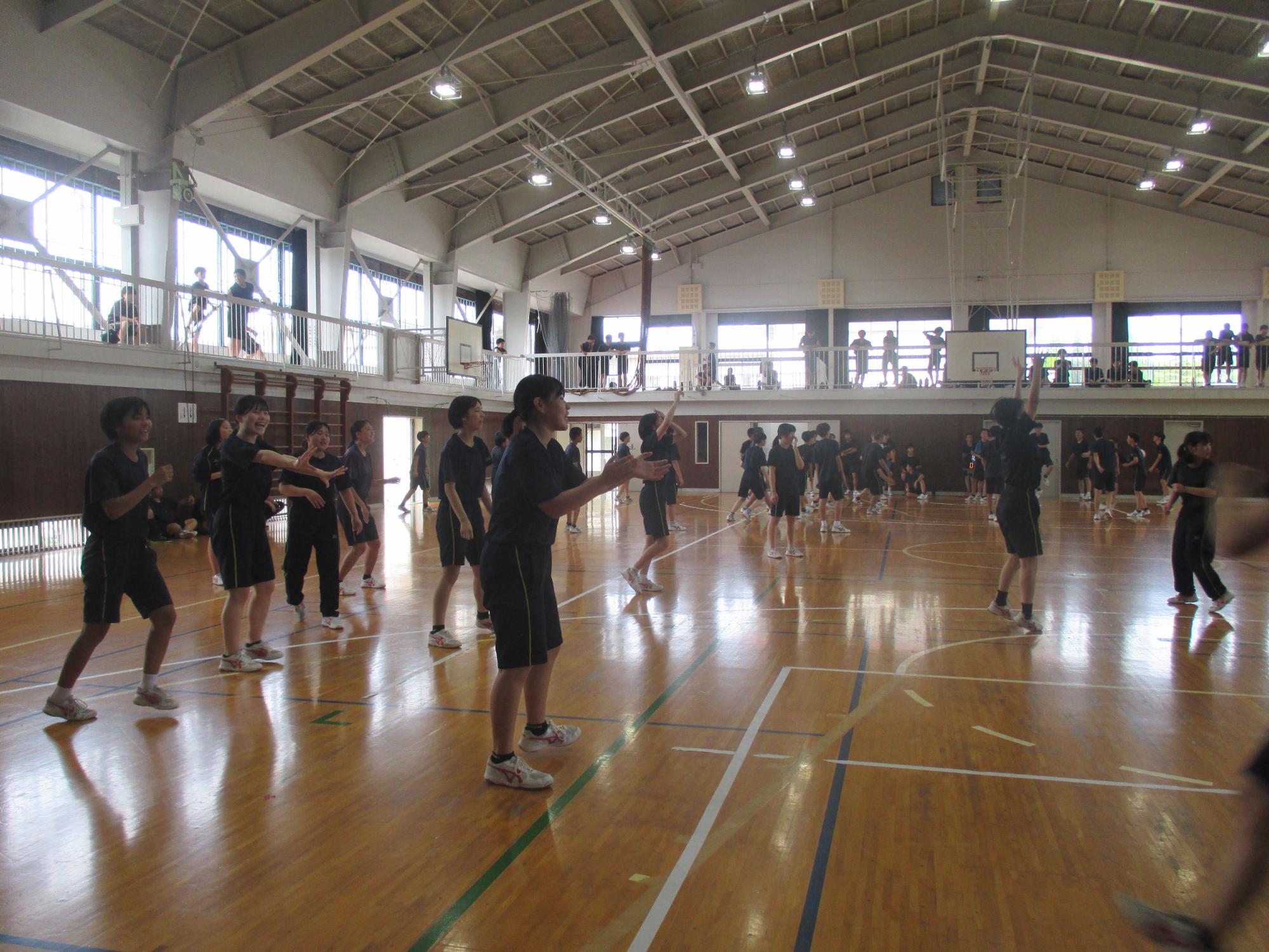 体育館でクラス対抗バレーボールをする生徒たちの写真