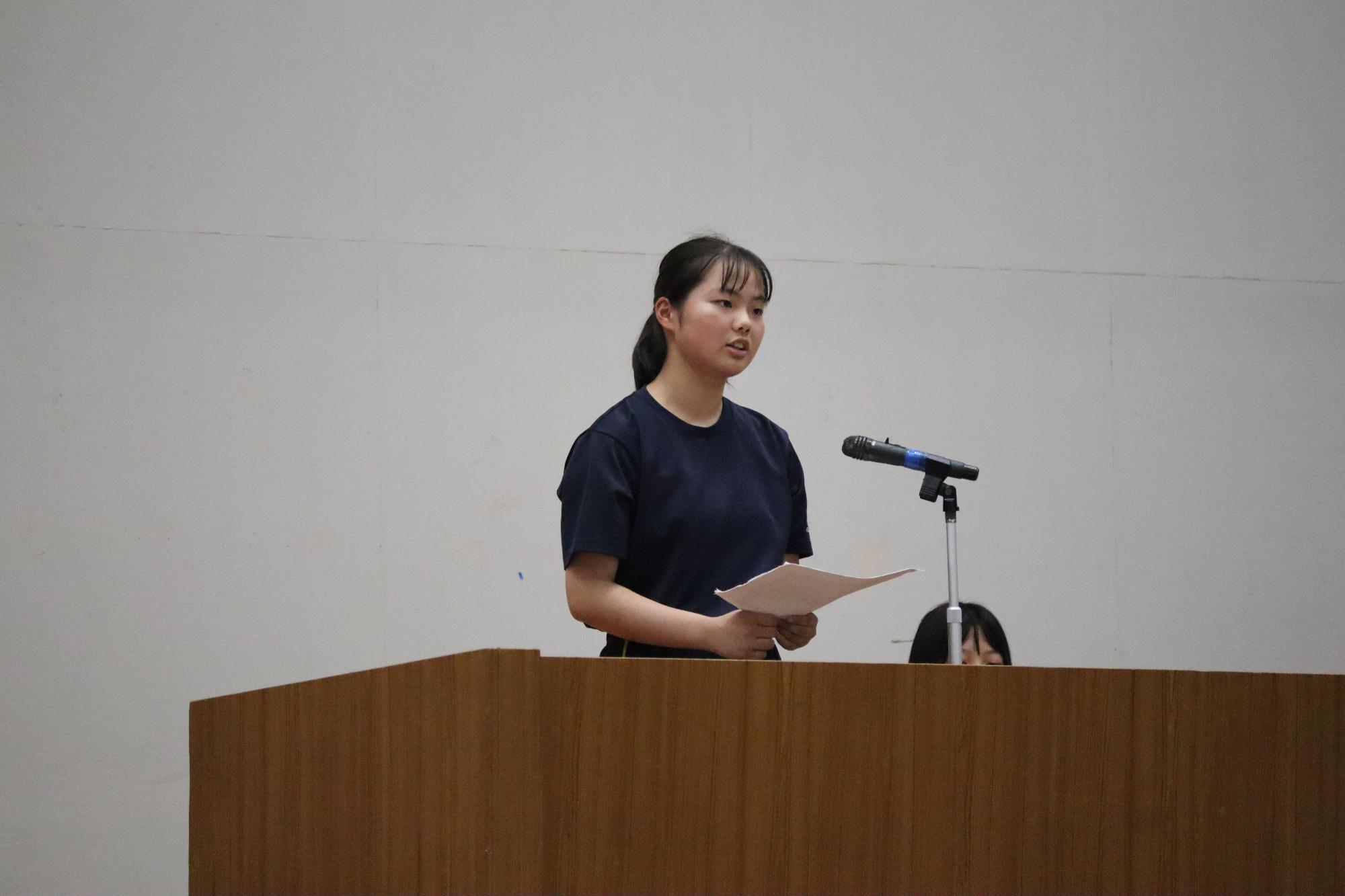 体育館で女子生徒が演説を行う写真