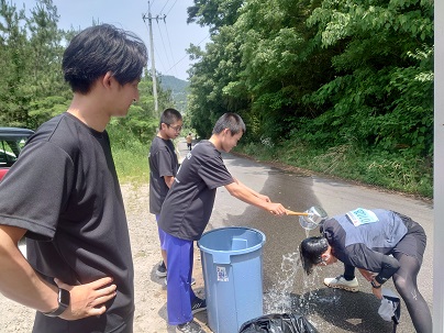 マラソンの給水ポイントで生徒が水をかけて仲間を応援している写真
