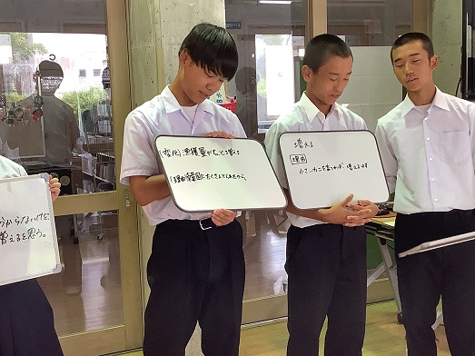 男子生徒が小さいホワイトボードを持って発表している写真