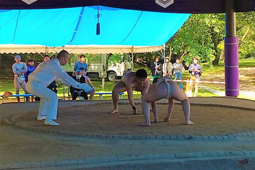 屋外の土俵で生徒たちが相撲の取り組みをしている写真