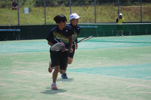 テニスコートで男子生徒2人がペアを組んでダブルスの試合をしている写真