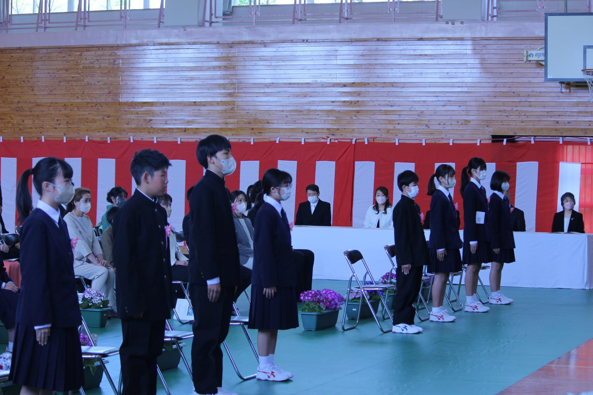 体育館で生徒たちが入学式に参加している写真