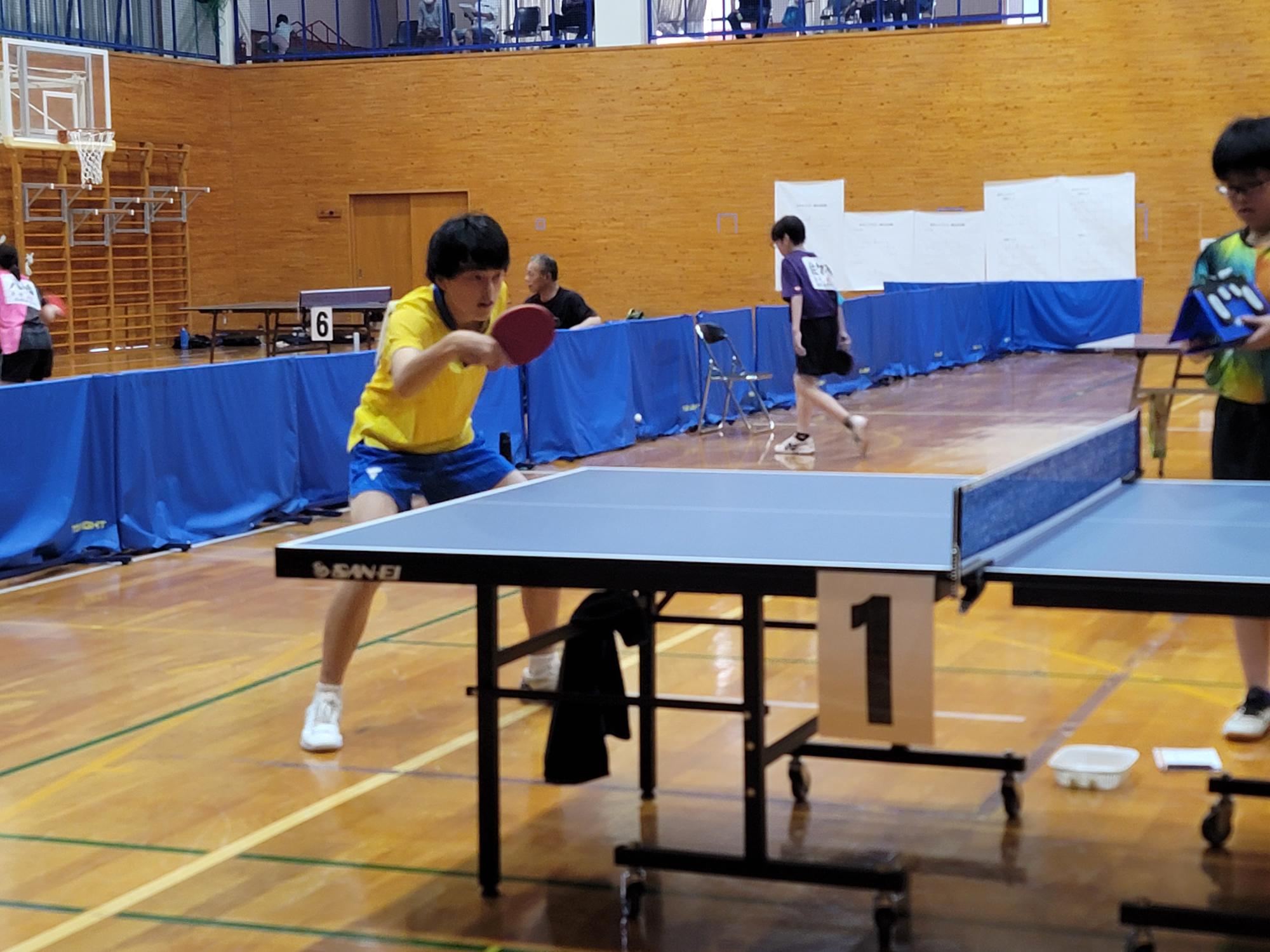 体育館で生徒が卓球の試合をしている写真