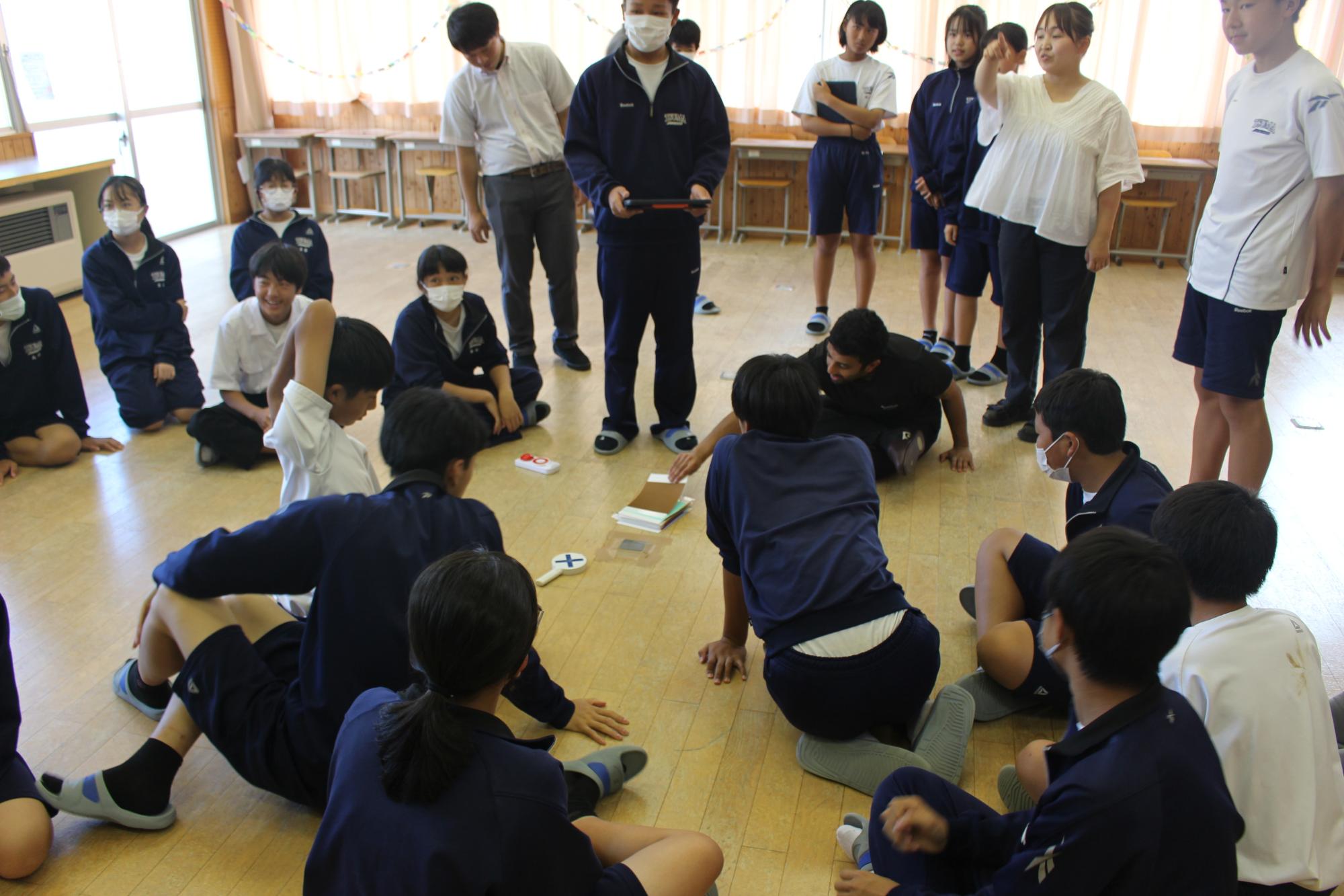教室に座ったり立ったりと様々な生徒たちが先生と交流している写真