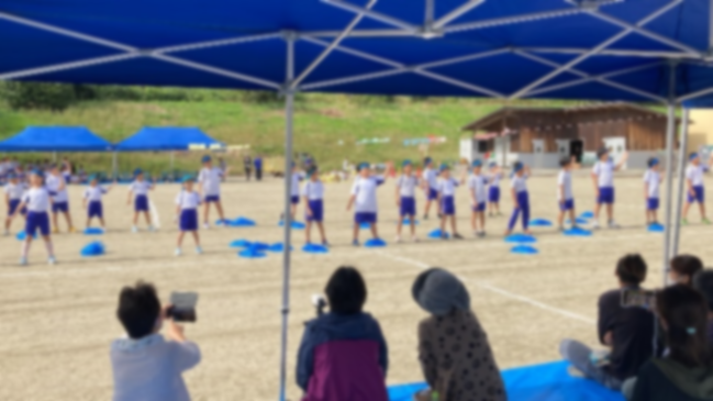 運動会で青い布を使った演技を披露する児童の写真