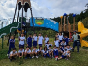 公園の遊具前で集合写真を撮るたくさんの児童の写真
