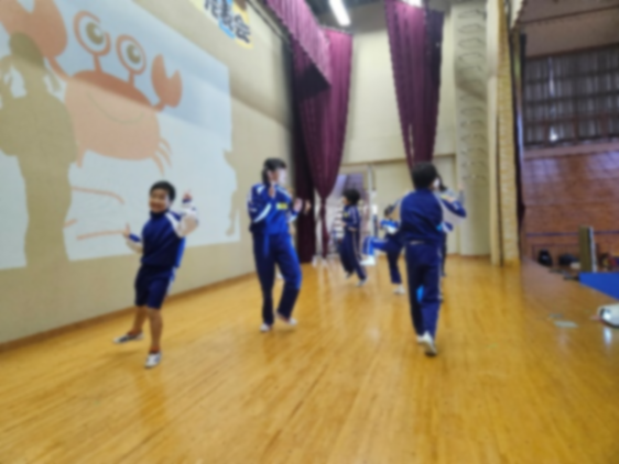 体育館のステージ上で回りながらダンスを披露する児童の写真