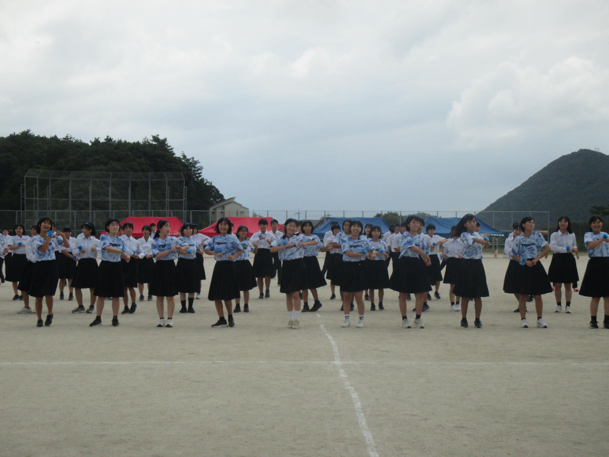 運動場で女子生徒がダンスを披露する写真