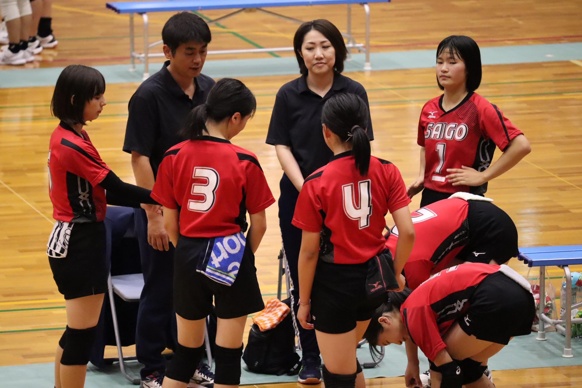 体育館で女子バレーボール部がミーティングをする写真