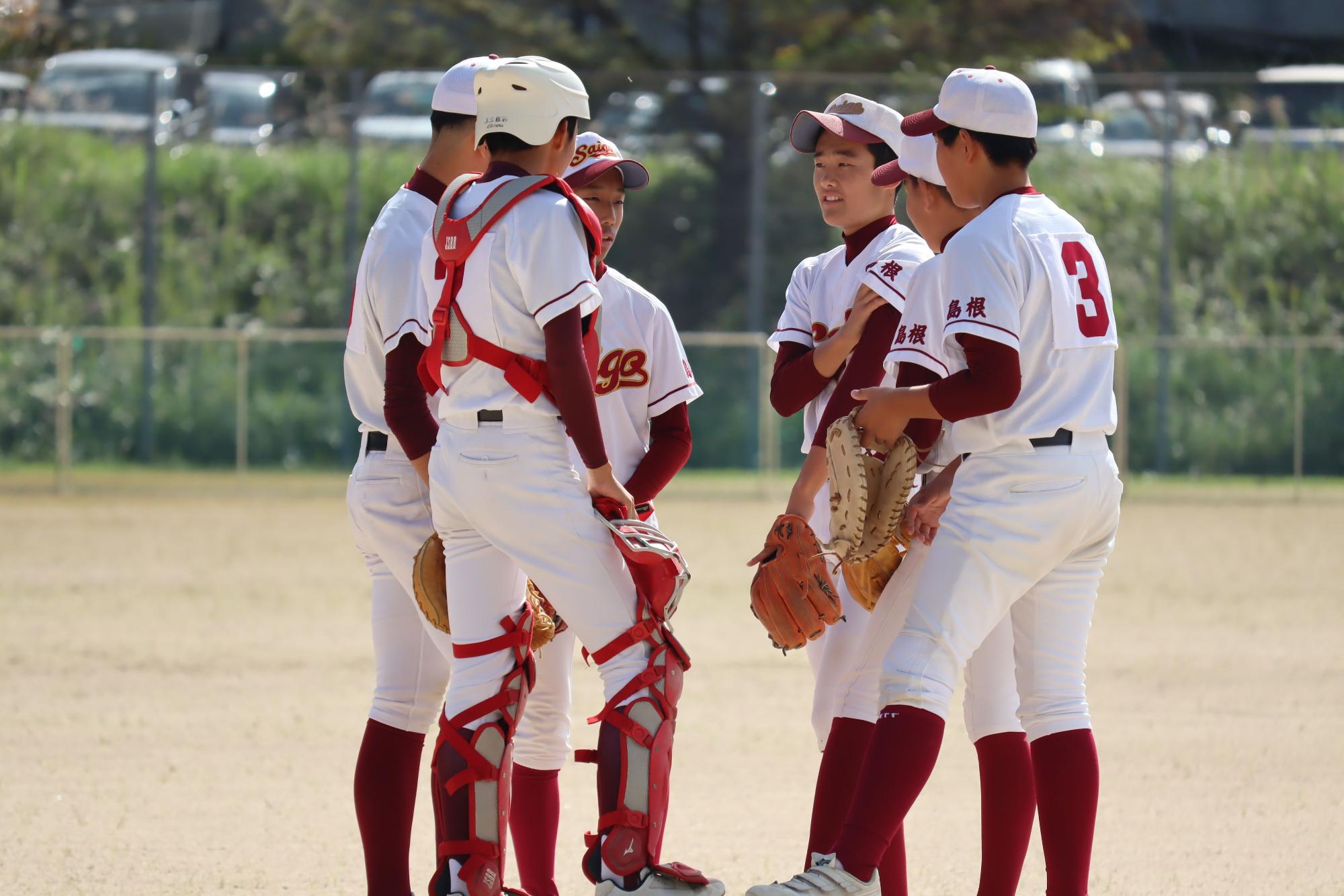 グラウンドで野球部の生徒たちが円陣を組む写真