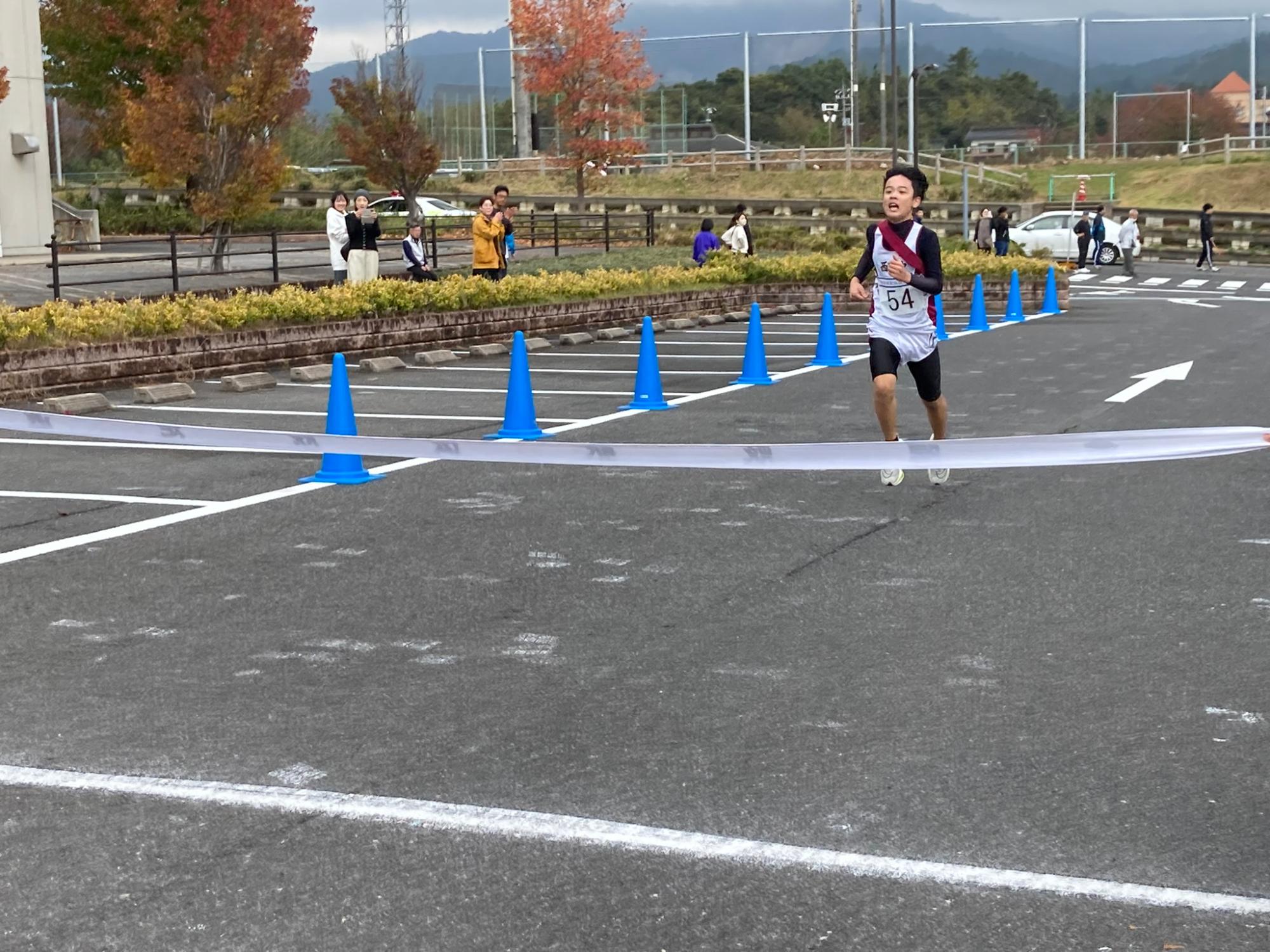 マラソン大会で男子生徒がゴールテープを切る写真