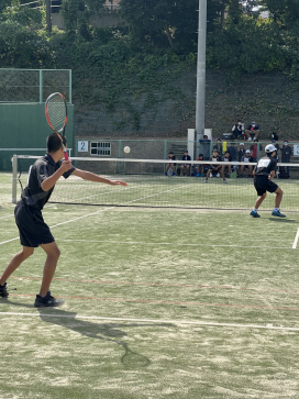 テニスコートで男子生徒が試合をしている写真