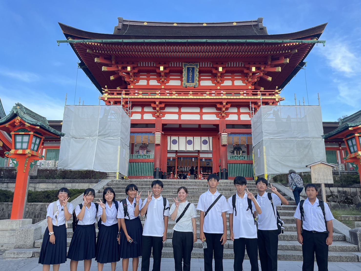 京都の神社の前で制服姿の生徒たちが記念写真を撮っている写真