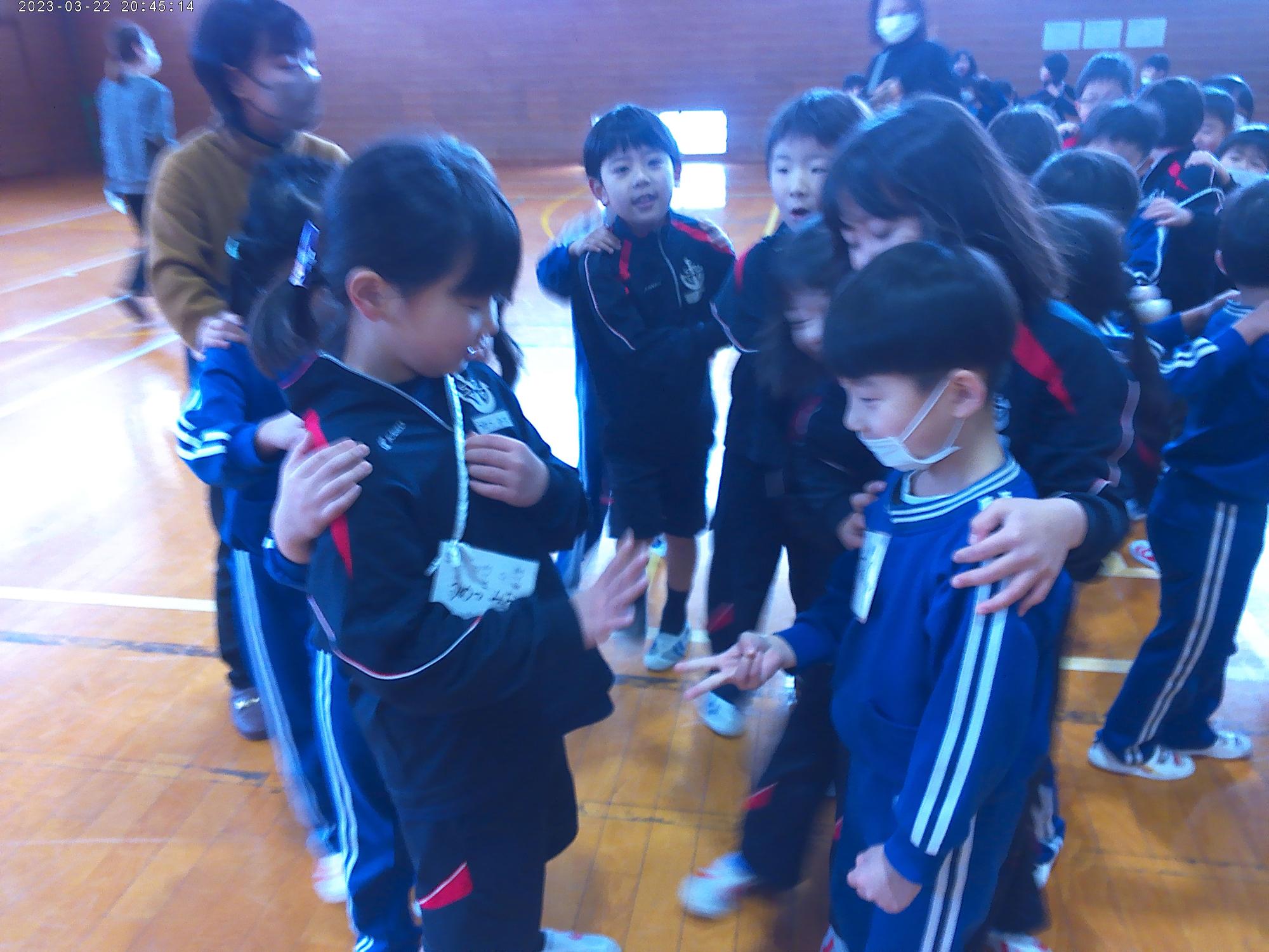 体育館で青いライトの下でジャンケンをする児童たちの写真