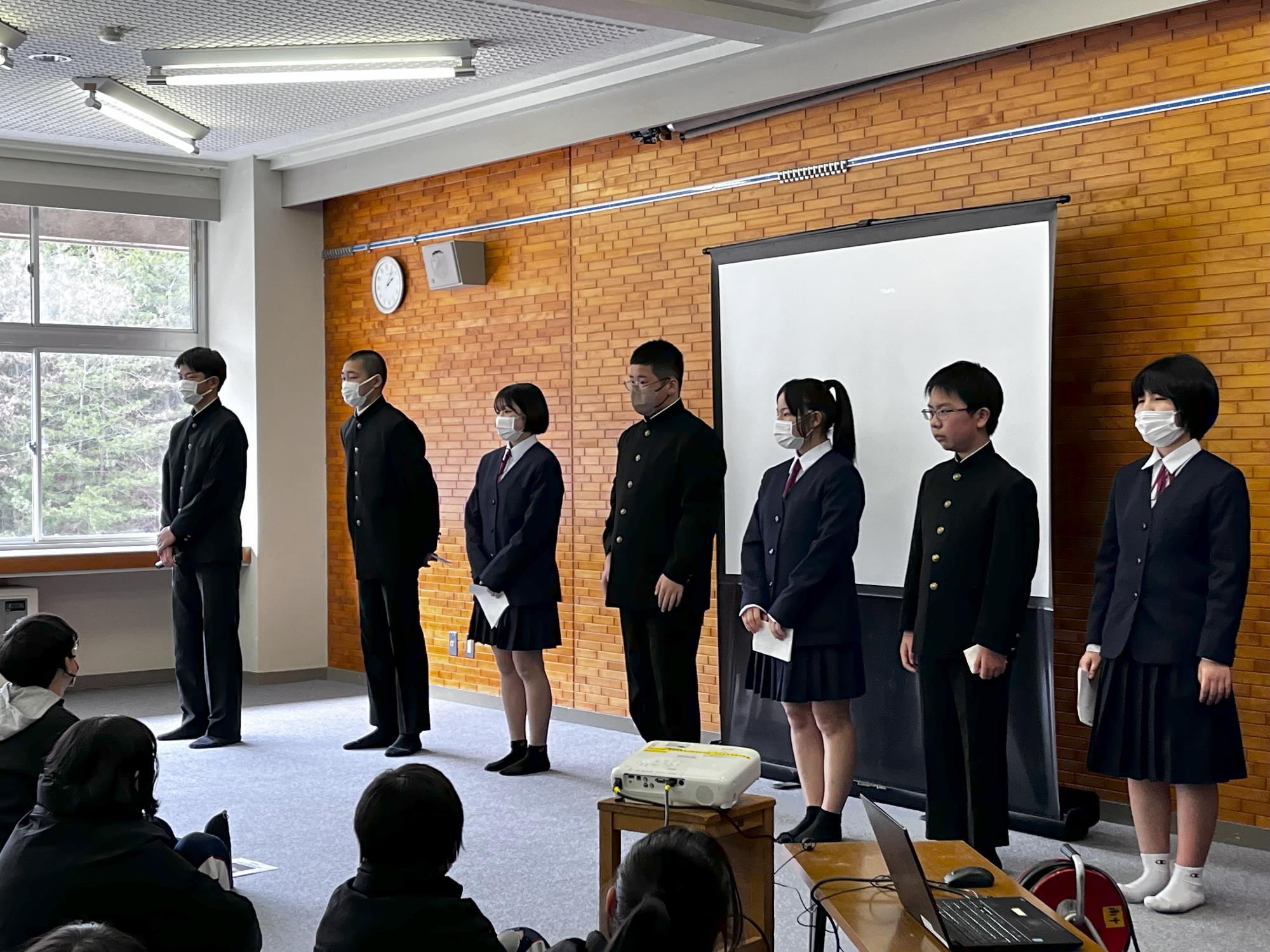 座っている生徒たちの前に並んだ生徒たちが発表会で整列している写真