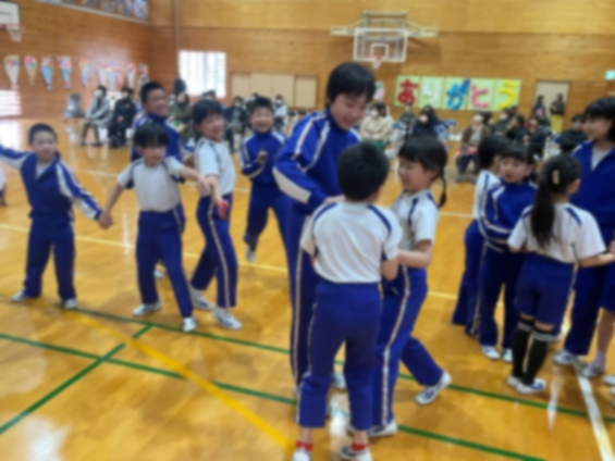 体育館で児童たちが笑顔で触れ合っている様子の写真