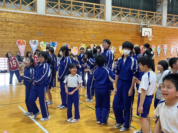 体育館で全学年の児童たちが集まり活動を楽しんでいる様子の写真