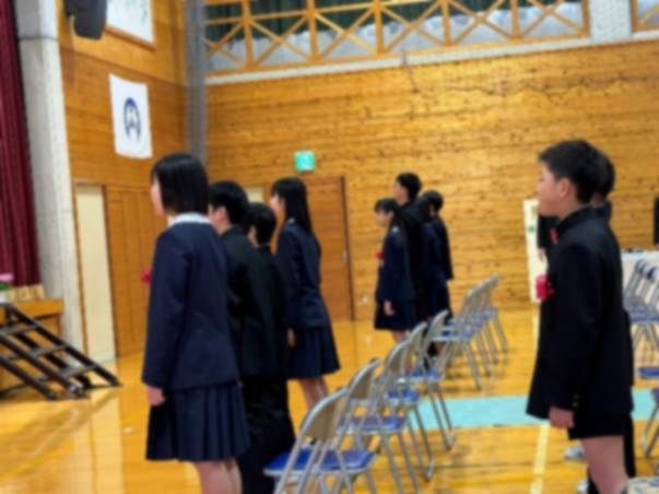 体育館で児童たちが整列して式に臨む様子を横から写した写真