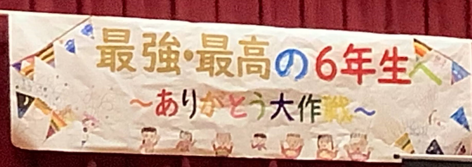 体育館の舞台に掲げられた「最強・最高の6年生へありがとう大作戦」と書かれた横断幕の写真