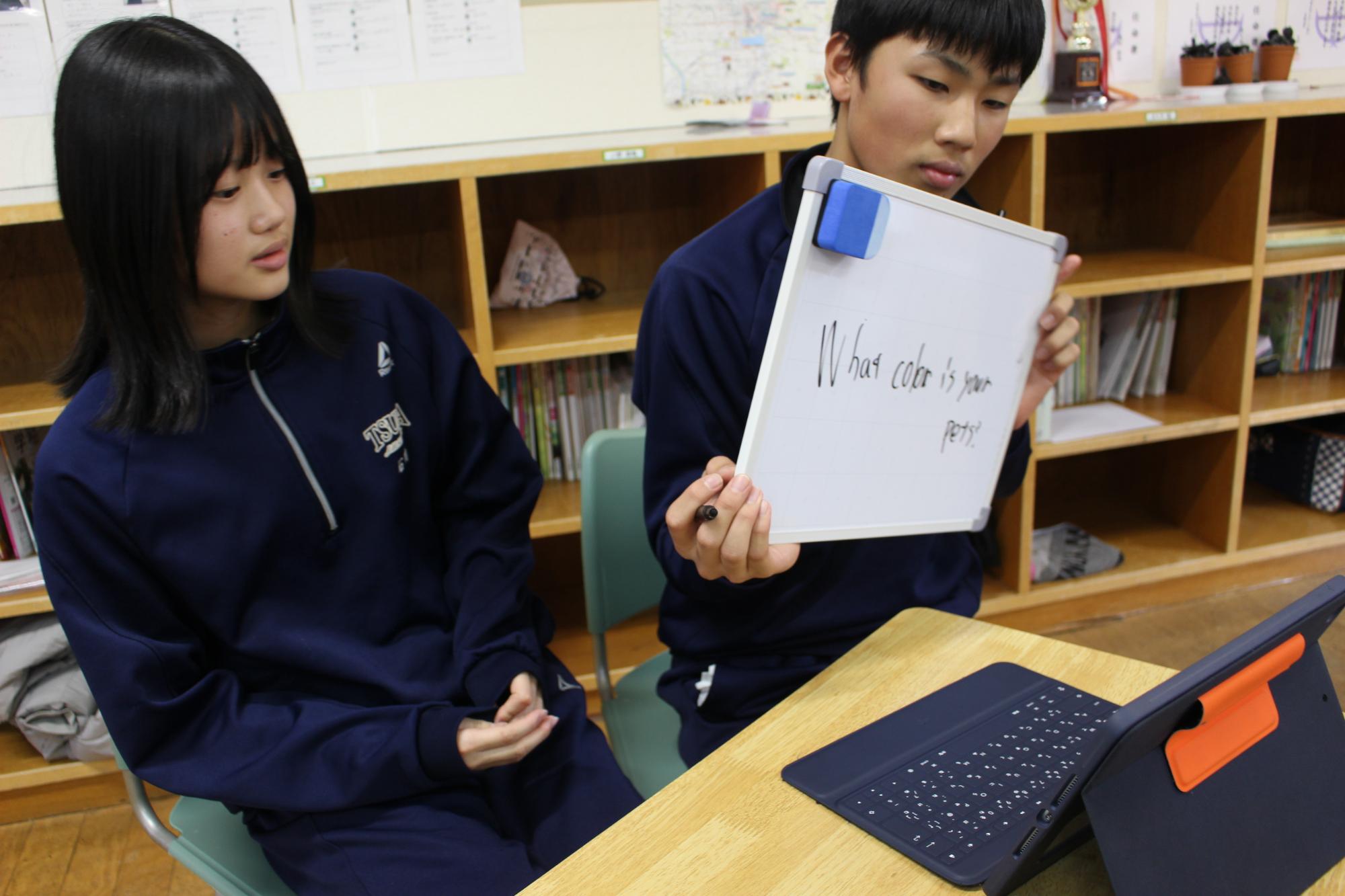 教室でホワイトボードを使って英語の会話練習をする生徒たちの写真