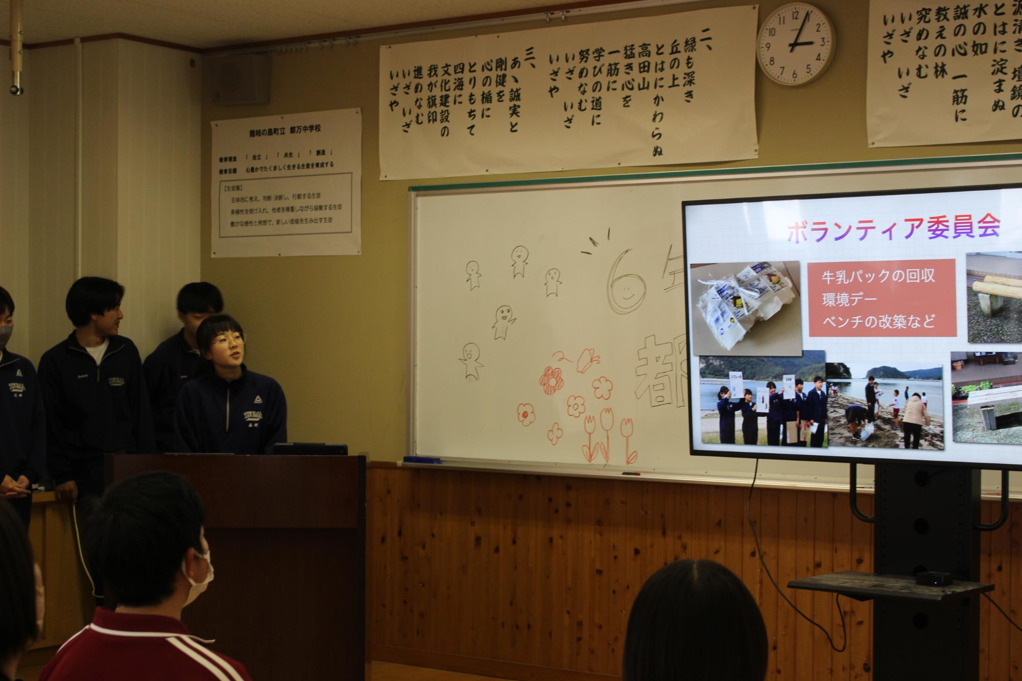 教室でボランティア委員会の活動を紹介する発表をする生徒たちの写真