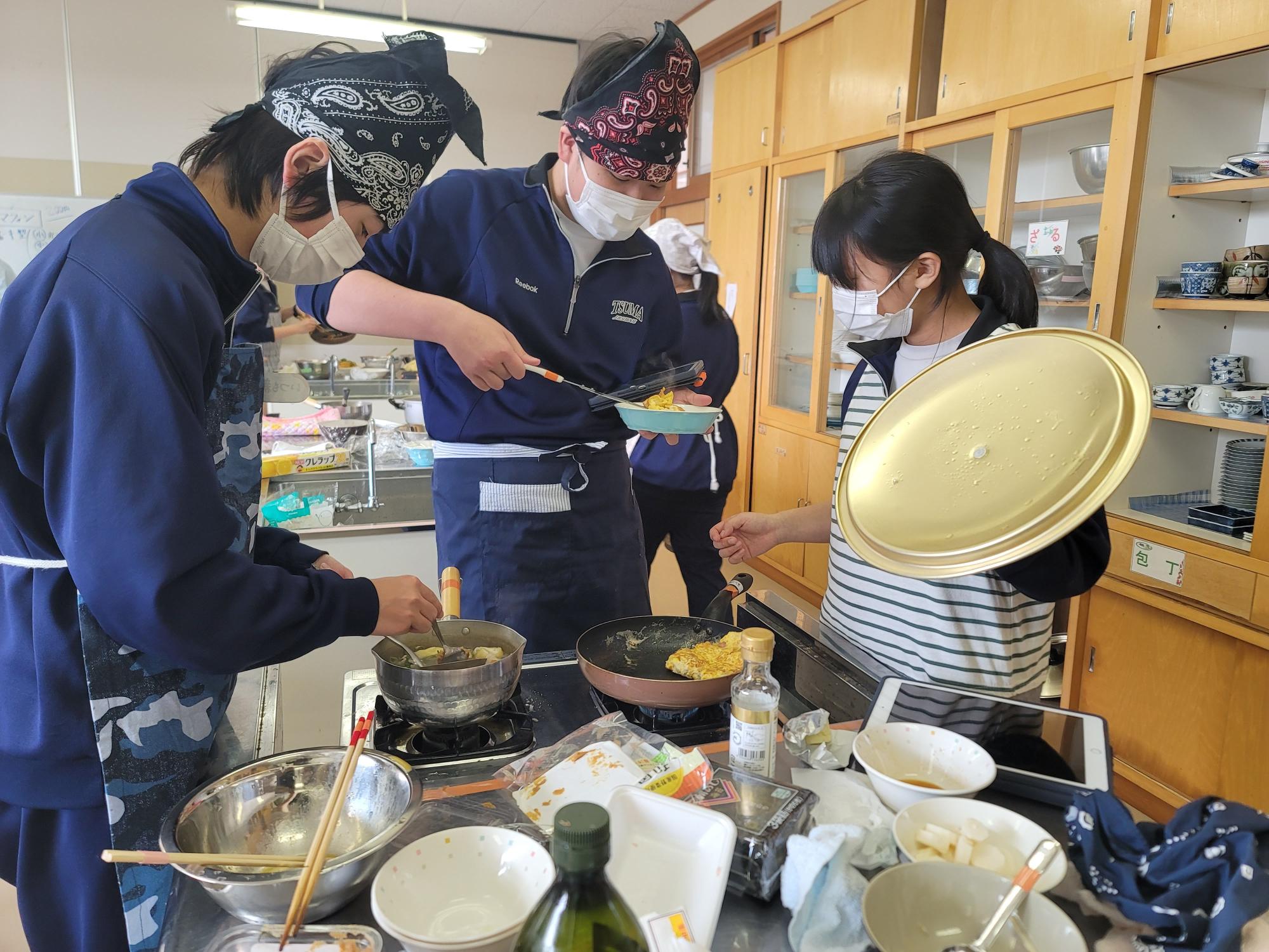 家庭科室でエプロンをつけて調理実習を行う生徒たちの写真