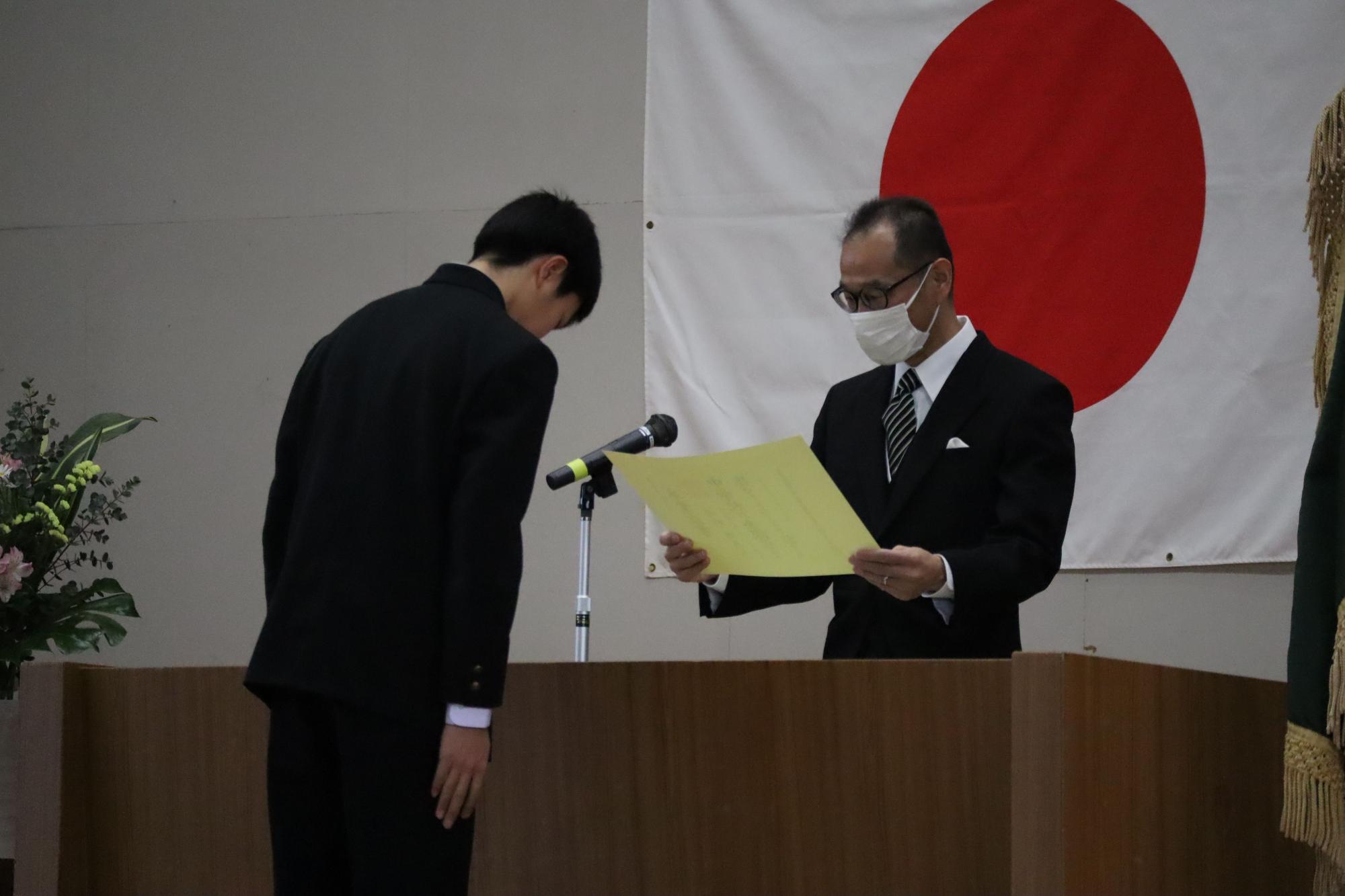 体育館の壇上で男子生徒が賞状を受け取っている写真