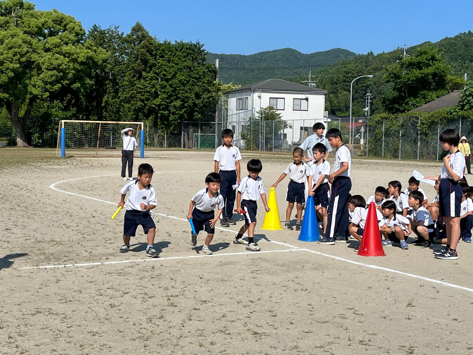 校庭で児童たちがリレーを行っている写真