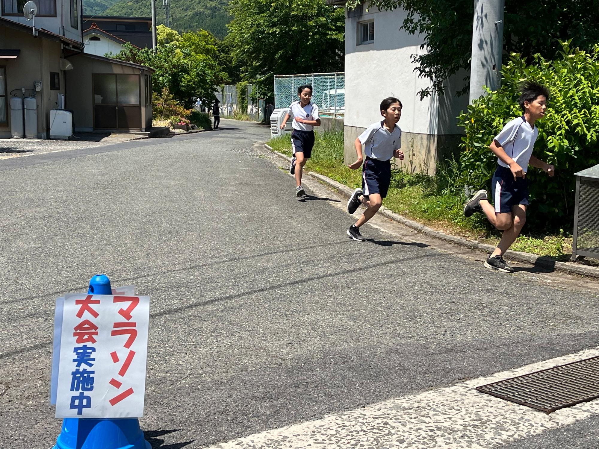 校外の道路で児童たちがマラソン大会を走っている写真