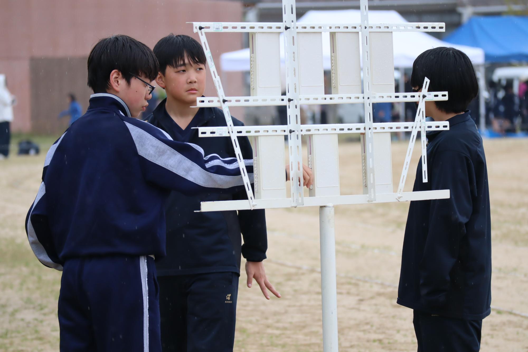 競技場で生徒たちが得点板を操作している写真