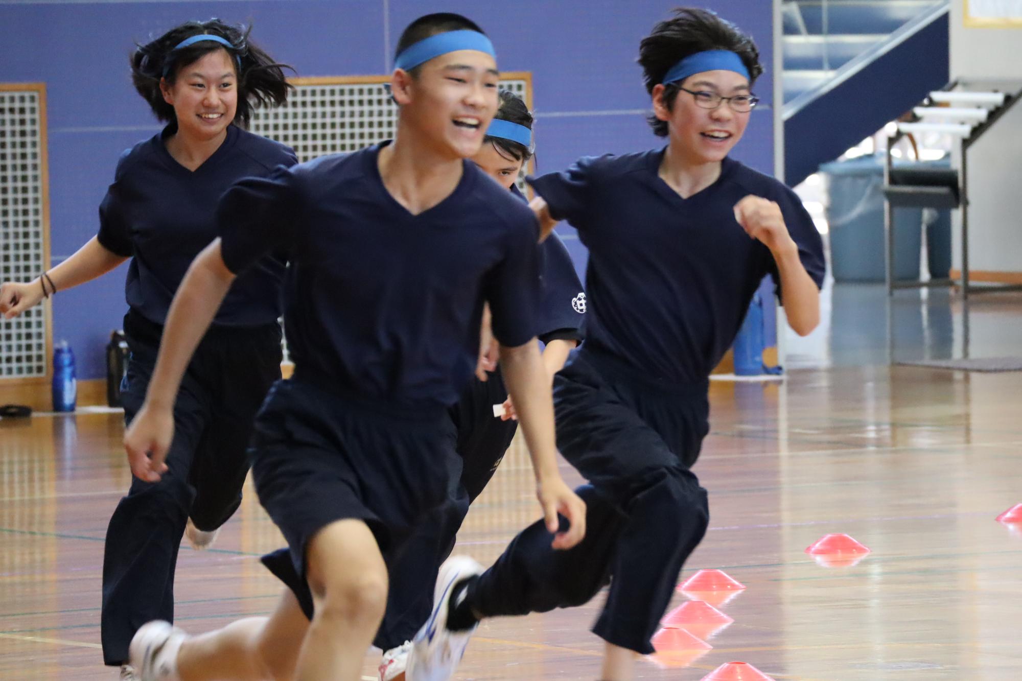 体育館で生徒たちが笑顔で走っている写真
