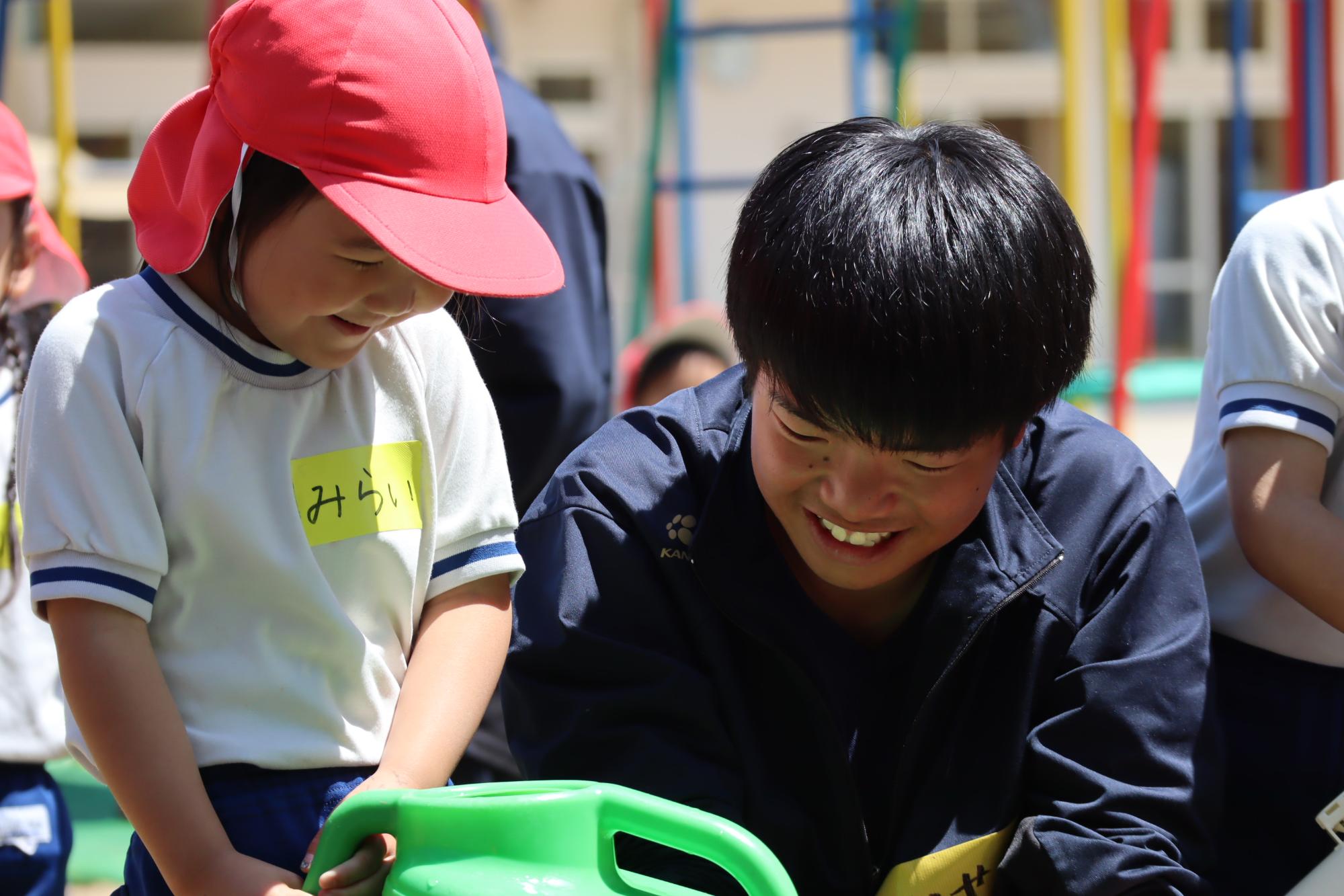児童と生徒が一緒に水やりをしている写真