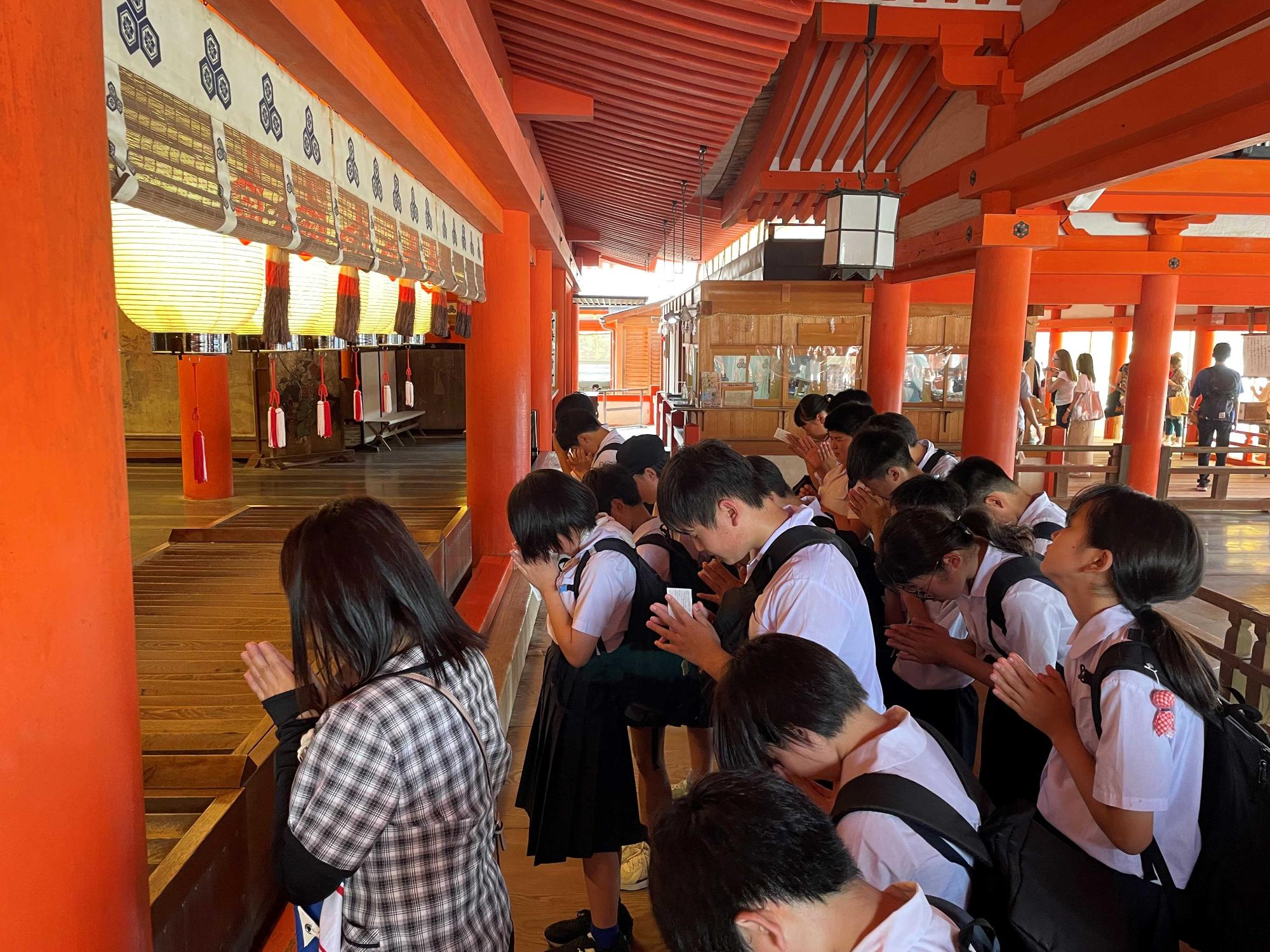 神社の拝殿前で生徒たちが並んで参拝している写真