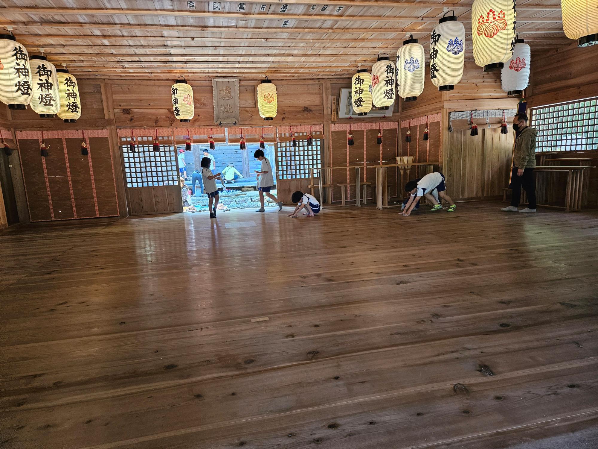 神社の広間で複数の児童が掃除をしている写真