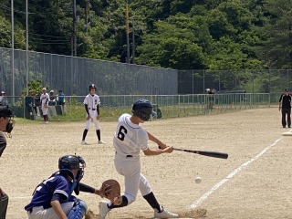 野球場で打席の生徒がバットでボールを打ち返している写真