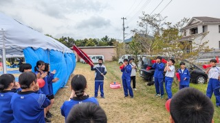 校庭のテント前で赤色のメガホンを持って応援する生徒たちの写真