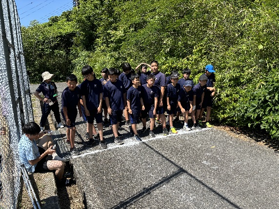 校庭横の道路で体操服を着た児童たちがスタートラインに並んでいる写真