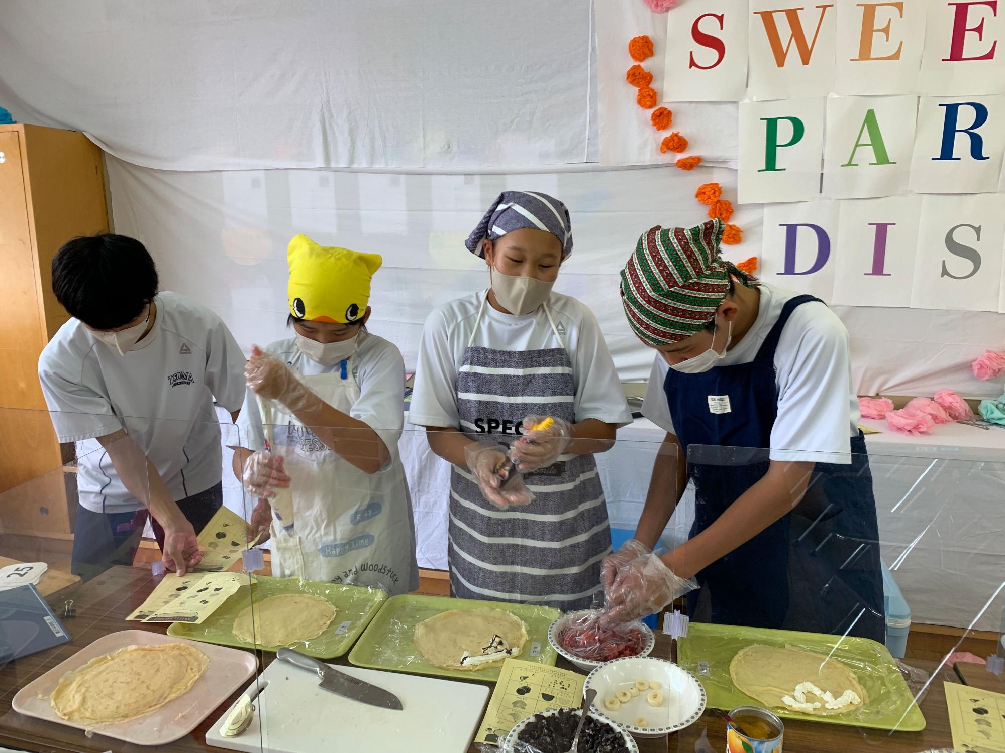 文化祭で生徒たちがエプロン姿でクレープを作っている写真