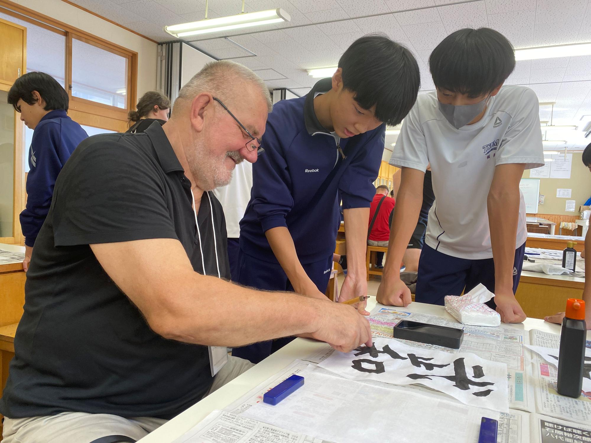 外国の講師と生徒たちが書道をしている写真