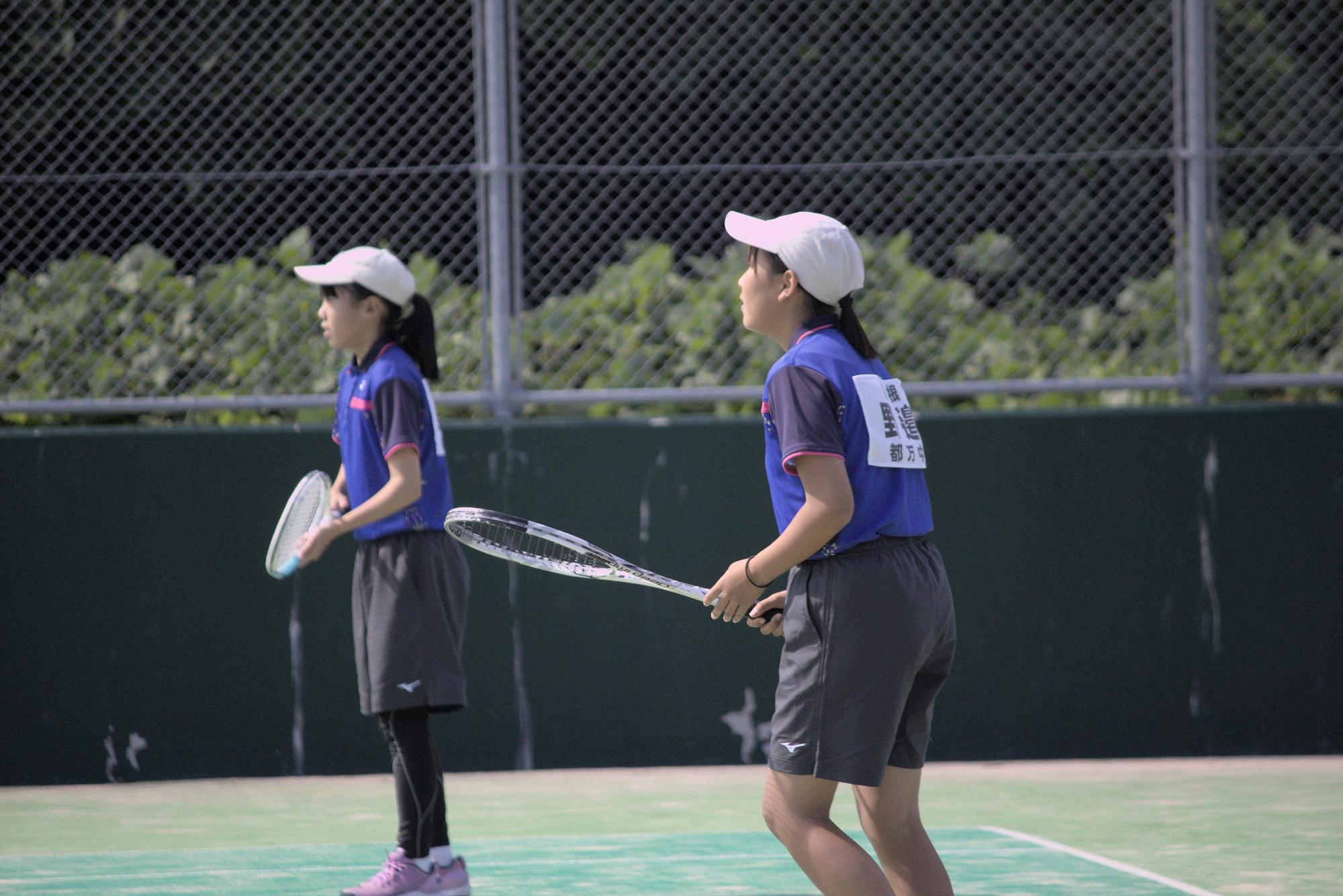 テニスコートで女子ペアが試合に臨んでいる写真