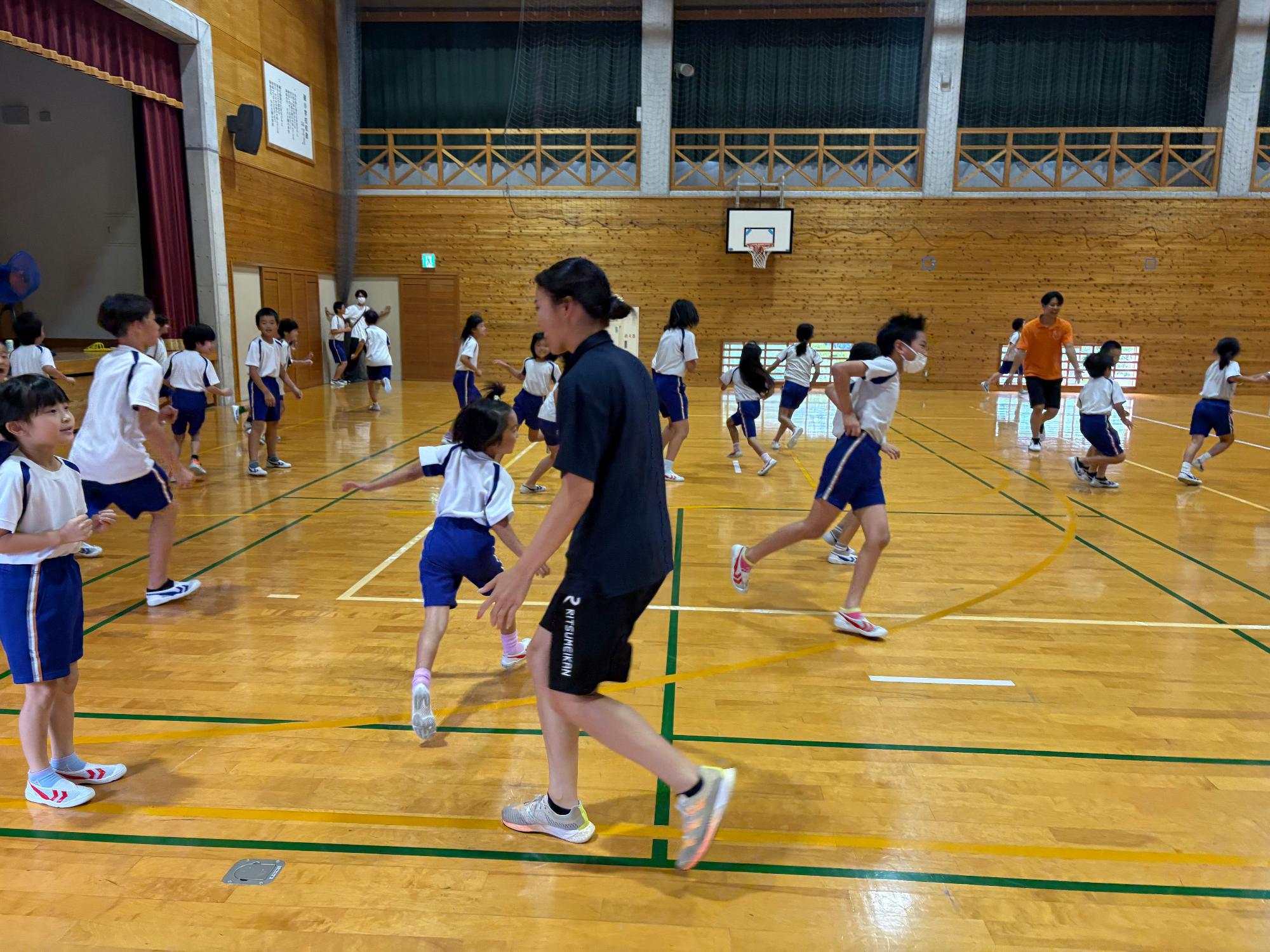 体育館で子どもたちが体を動かして遊んでいる写真