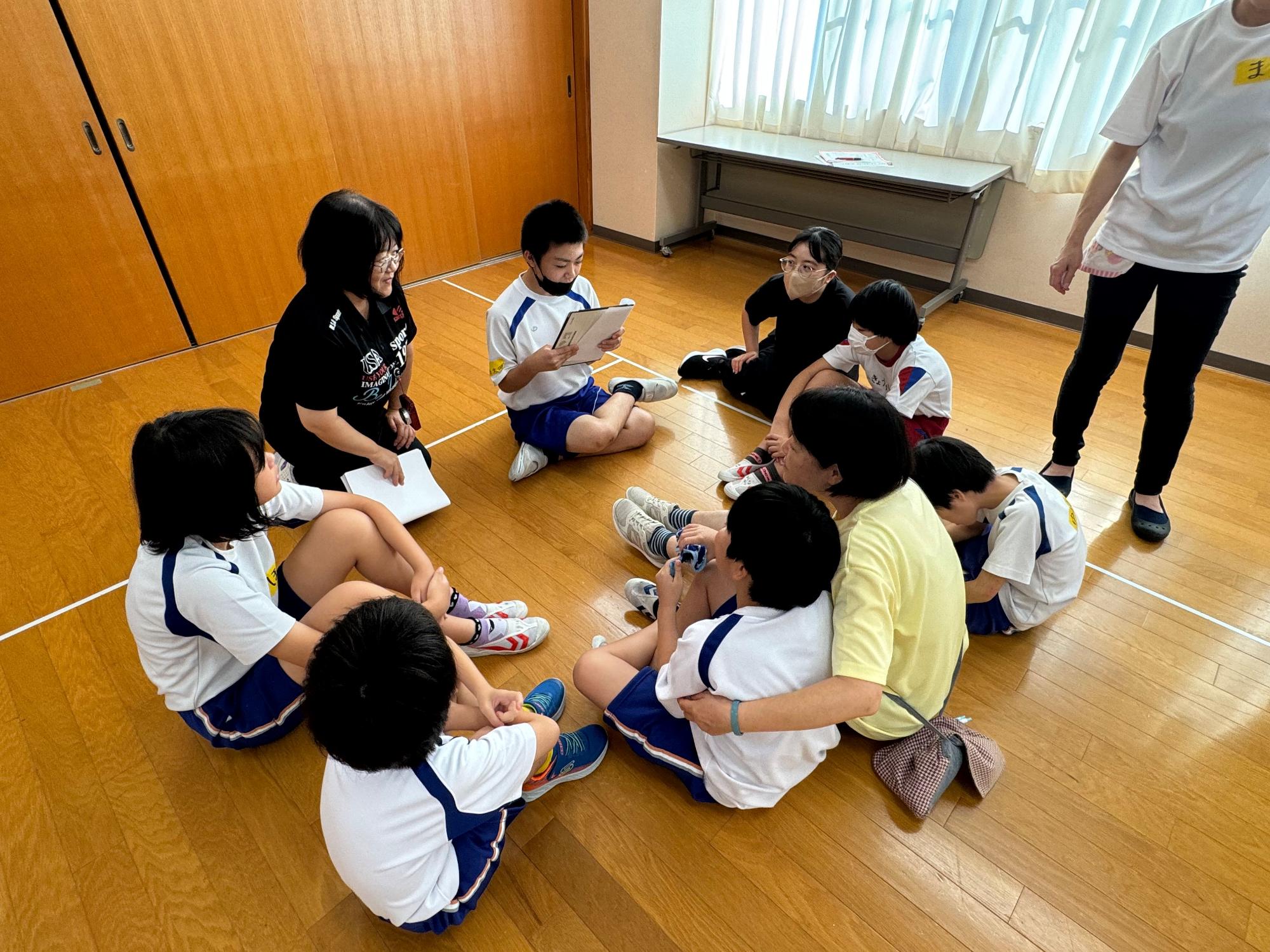 体育館で児童が輪になって発表している写真