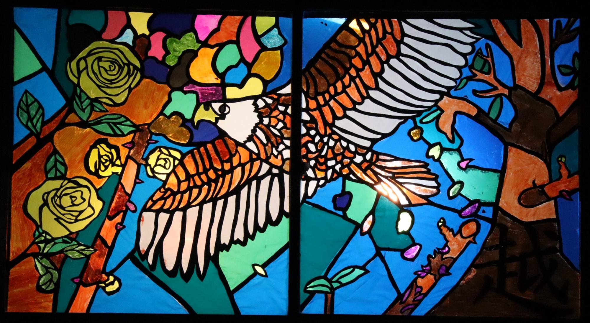 カラフルな羽を広げた鳥が描かれたステンドグラス風の作品の写真